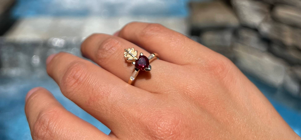 Ruby heart-cut engagement ring with baguette diamond accents on a gold band